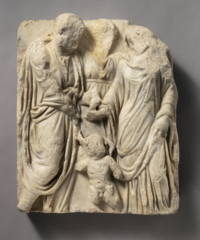 A worn marble relief of a Roman couple clasping hands at their wedding