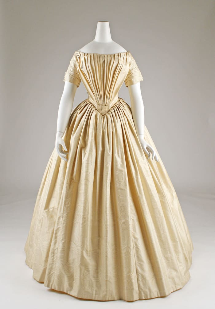 A cream silk wedding dress from about 1844 with an off-the-shoulder bodice and full skirt